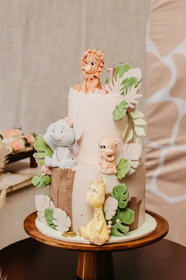Two-tier safari baby shower cake with fondant lion, elephant, giraffe and tropical leaves