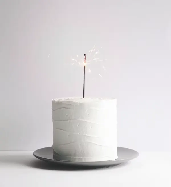 Minimalist white buttercream farewell cake with a lit sparkler candle