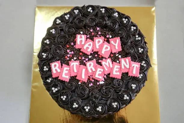 Chocolate retirement cake with pink 'Happy Retirement' lettering and chocolate rosettes
