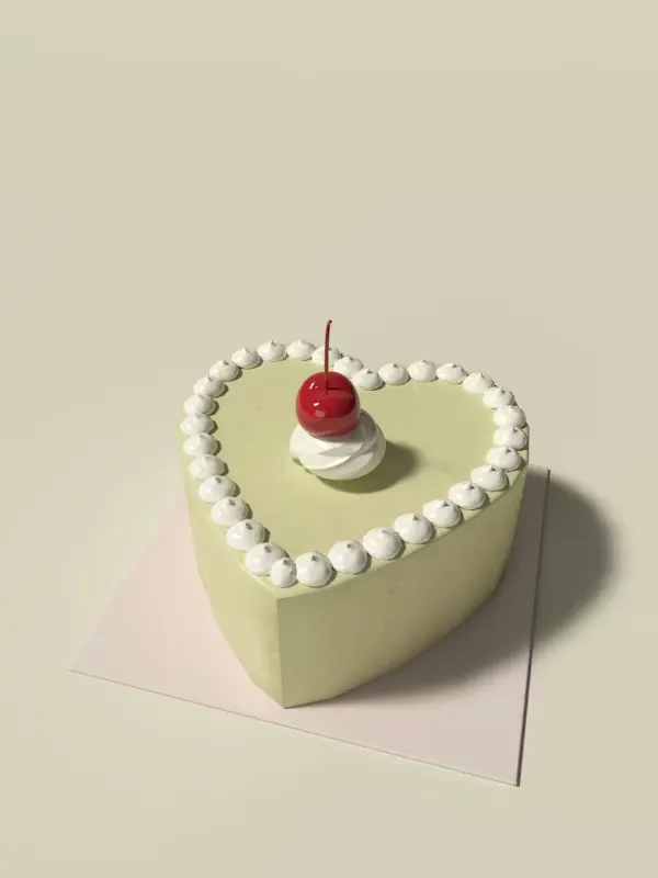 Small heart-shaped pistachio bento cake with a piped white border and a single glossy cherry on top