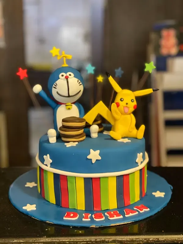 Blue and rainbow-striped cartoon cake topped with fondant figures of two animated best friends