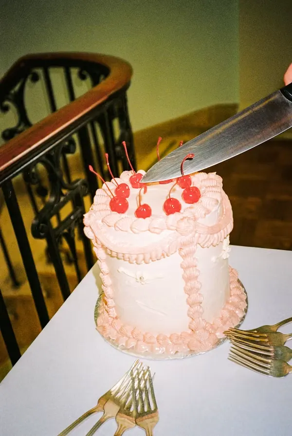 Vintage-style blush pink cake with shell piping and glace cherries on top